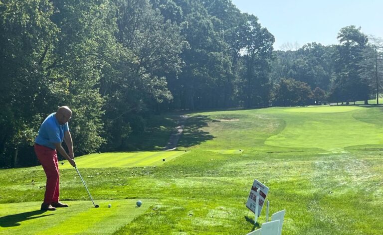 Man about to swing a golf club at the tee